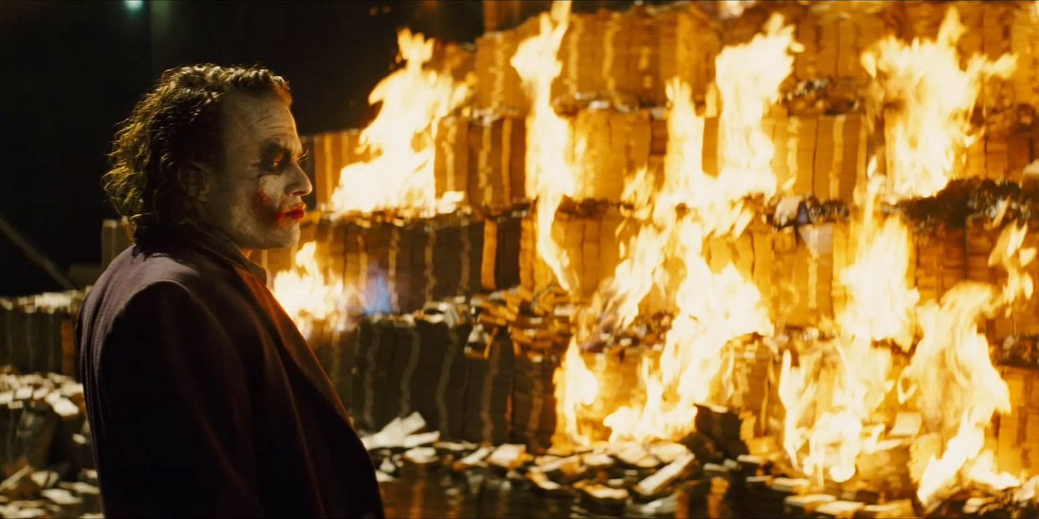 Хит Леджер в роли Джокера, сжигающего деньги в фильме "Темный рыцарь"