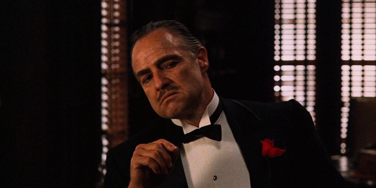 Дон Корлеоне у костюмі та у сидячому положенні у фільмі "Хрещений батько".