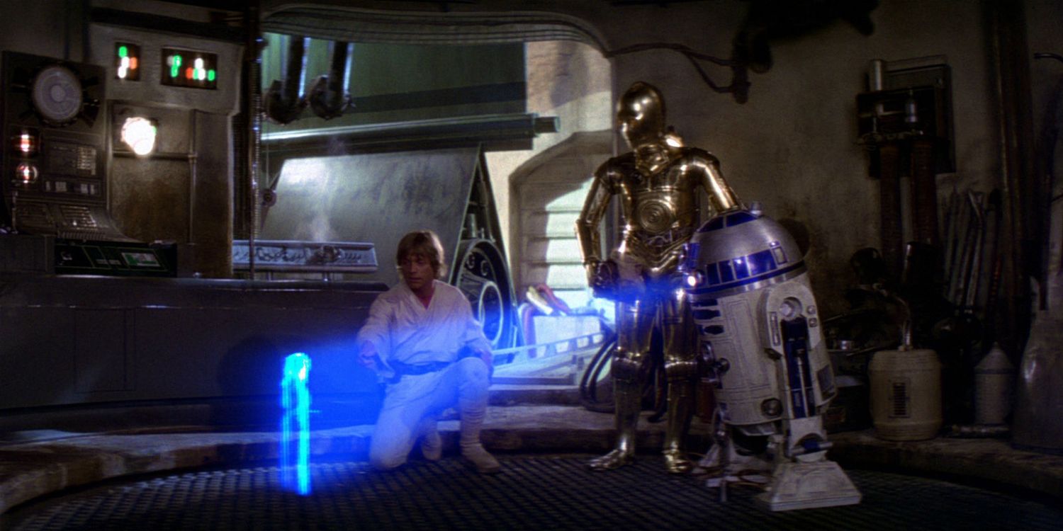 Люк Скайуокер та C-3PO дивляться, як R2-D2 показує голограму принцеси Леї у фільмі "Зоряні війни: Нова надія".