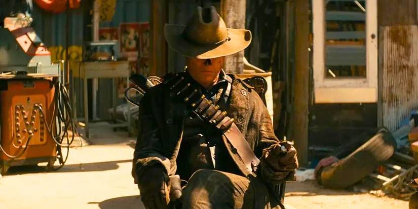 Уолтон Гоггінс у ролі Гуля сидить на стільці з ковбойським капелюхом, нахилившись над очима, в західному містечку на Amazon's Фолаут
