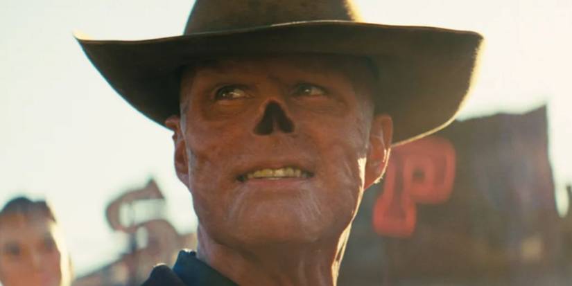 Волтон Гоггінс як Гуль підмигує підступною усмішкою, дивлячись убік у занедбаному західному містечку у серіалі Фолаут